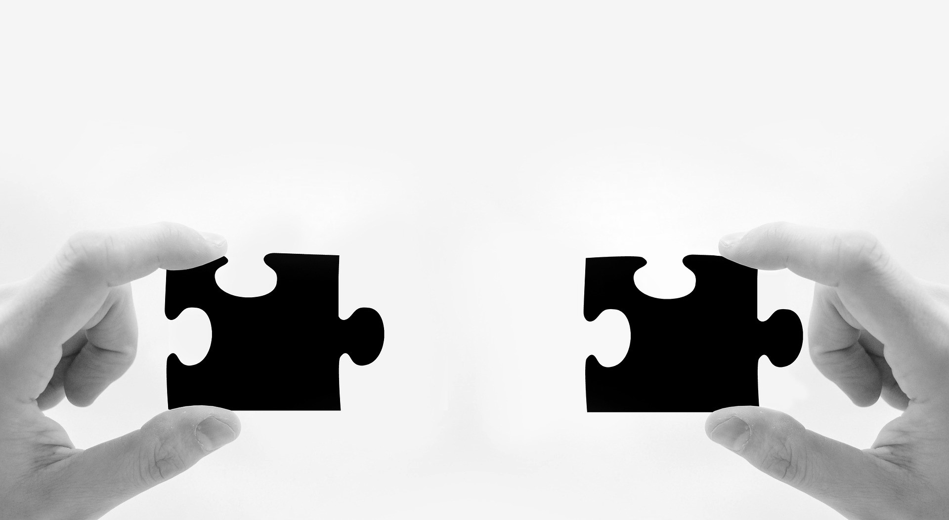 Hands holding two puzzle pieces about to connect