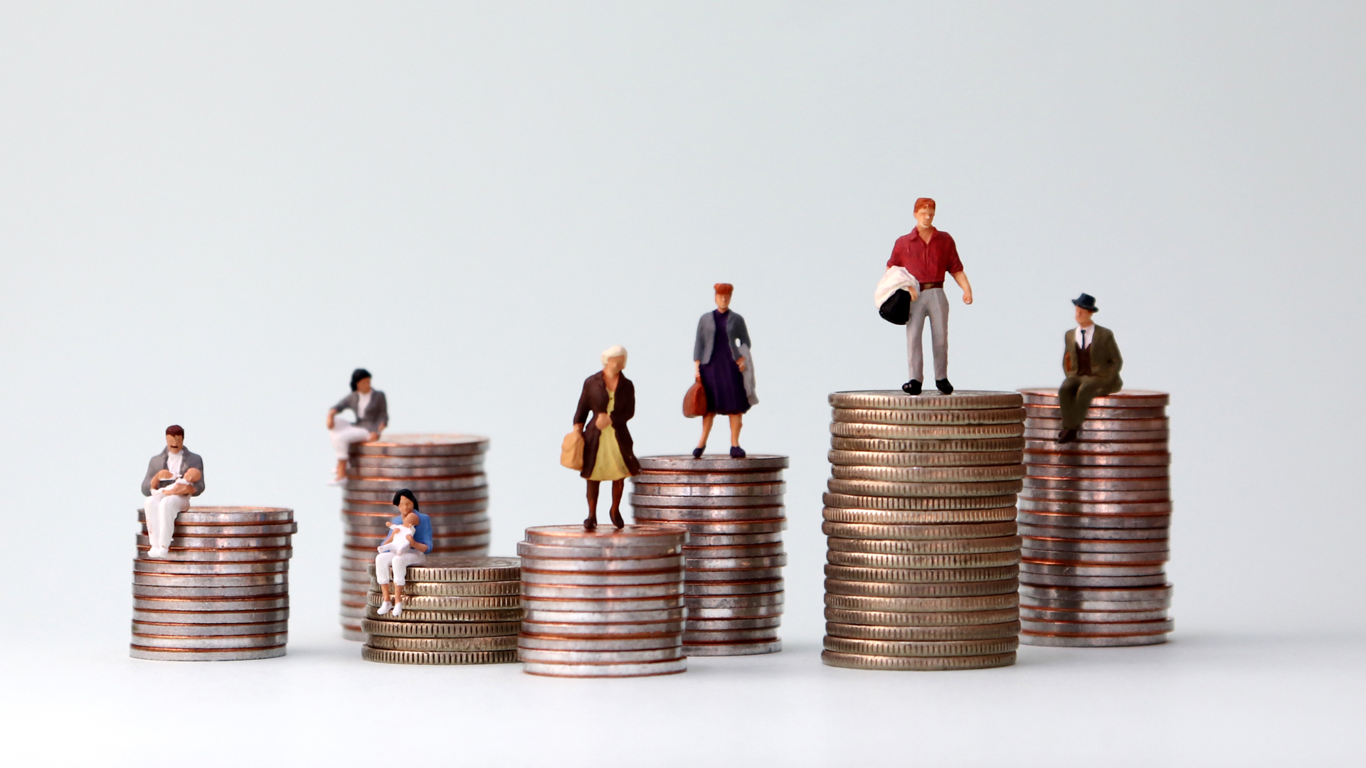  Miniature people positioned on stacks of coins of different heights.
