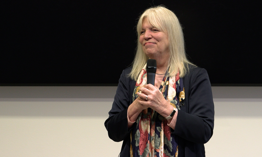  Laura T. Starks speaking on stage with a microphone.