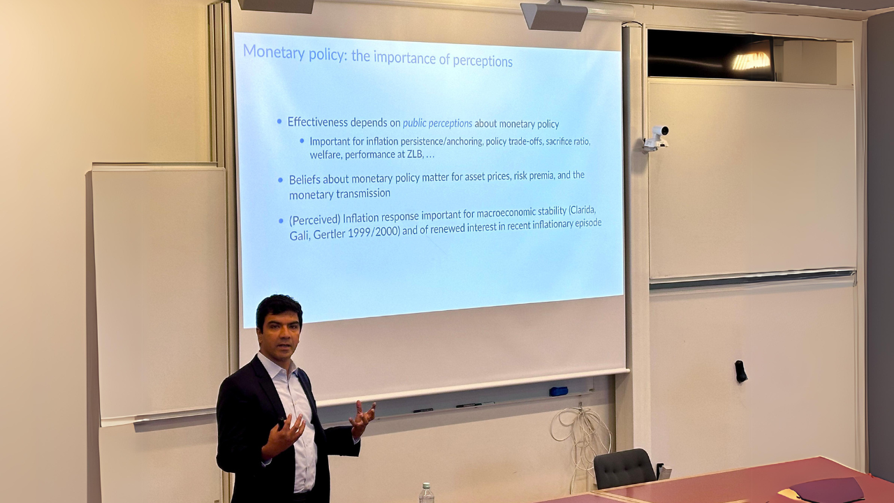 Adi Sunderam presenting a slide with the title "Monetary policy: the importance of perceptions"