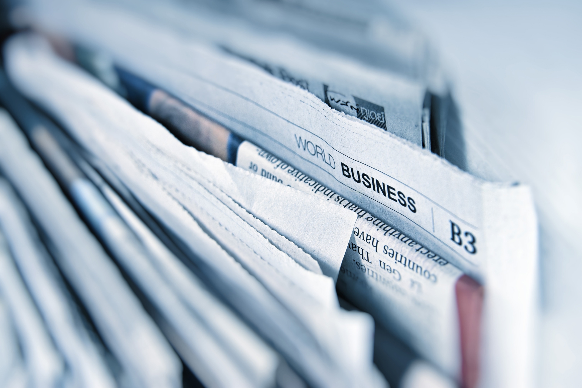 Stack of newspapers with a business news section visible