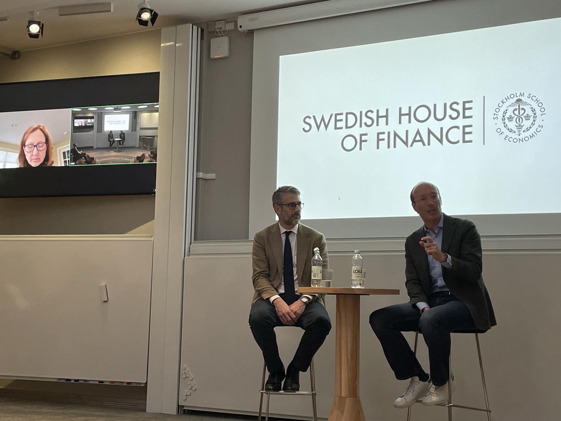 Two speakers sitting in front of a presenting screen