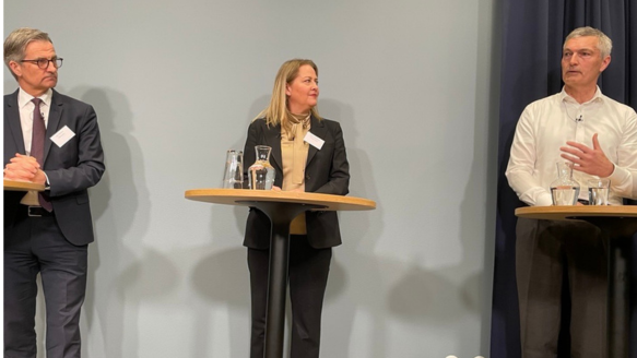 Three panelists speaking during a finance policy discussion