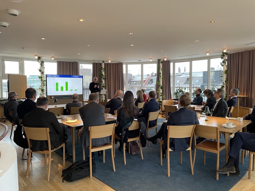 Audience attending a seminar presentation with financial charts displayed on a screen